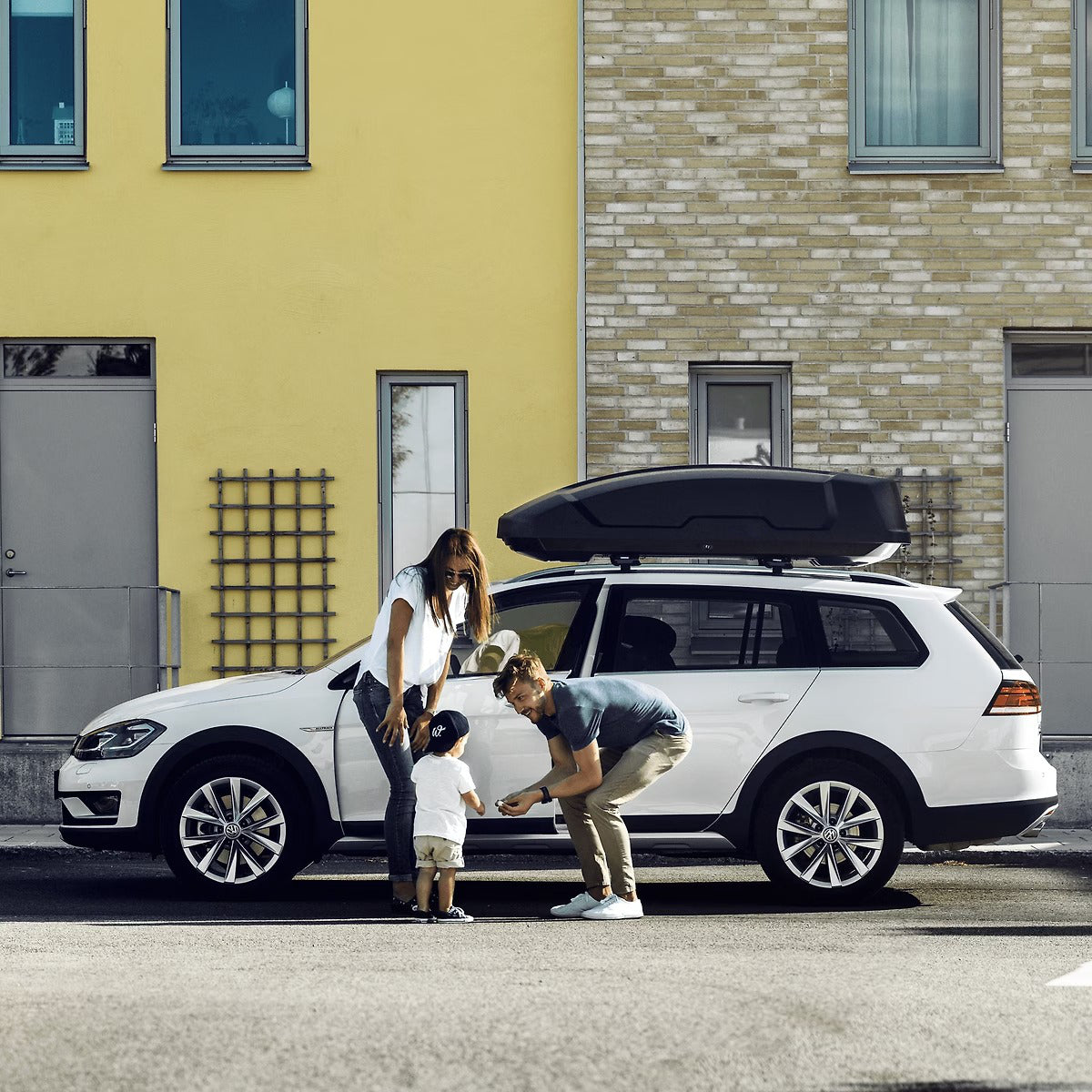 Family with a car and roof box in front of a building