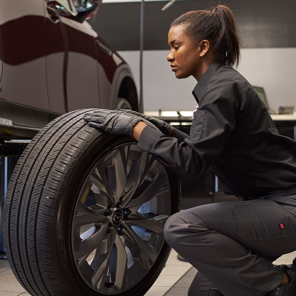 Person inspecting a car tire in a workshop setting