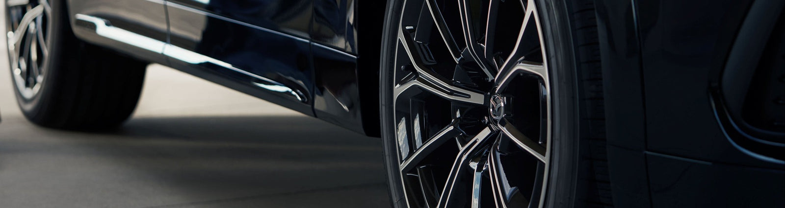 Close-up of a car wheel with a shiny rim on a blurred background